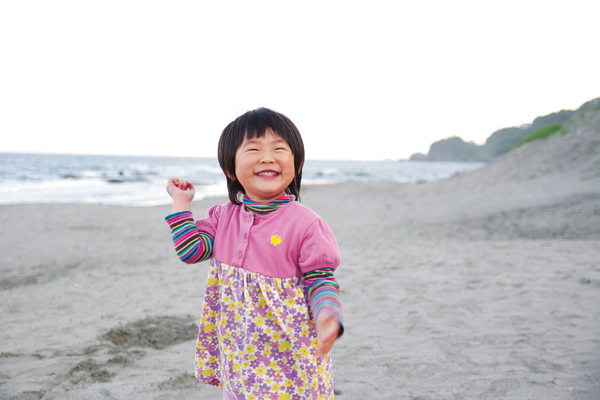 砂浜をバックに笑う子供の写真