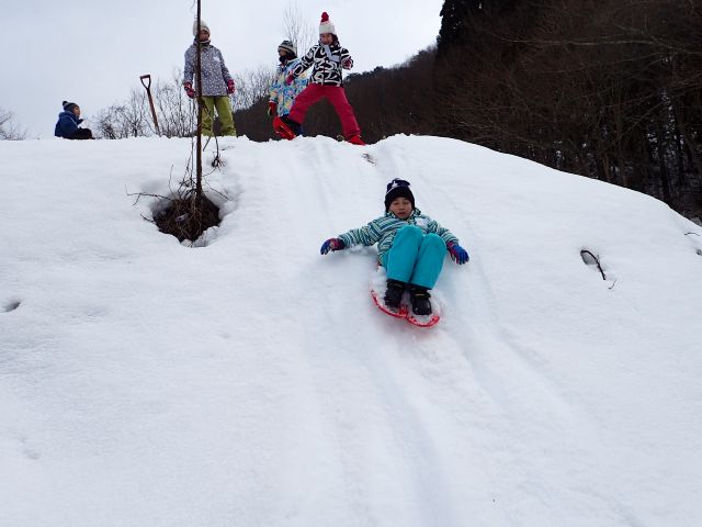 雪の滑り台で遊ぶ子供の写真