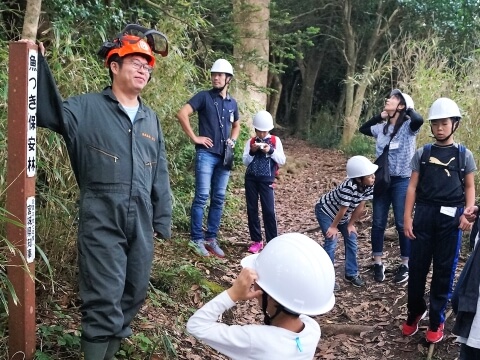 林業を営む佐藤太一さんとヘルメットを被った子どもたち（写真）