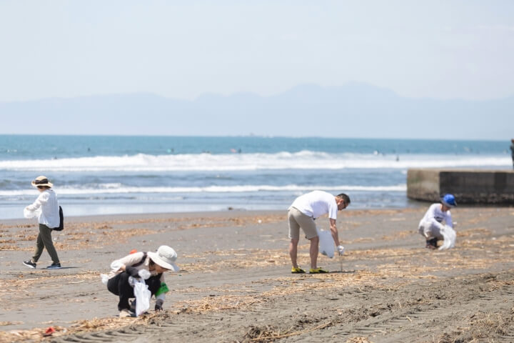 海岸で腰を屈めてゴミを拾っている参加者の写真