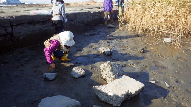 ぬかるんだ砂地にしゃがみこんでいる参加者