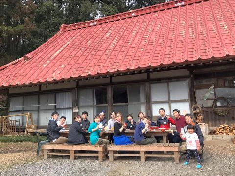 赤い屋根の民家の庭先で食事する参加者の写真