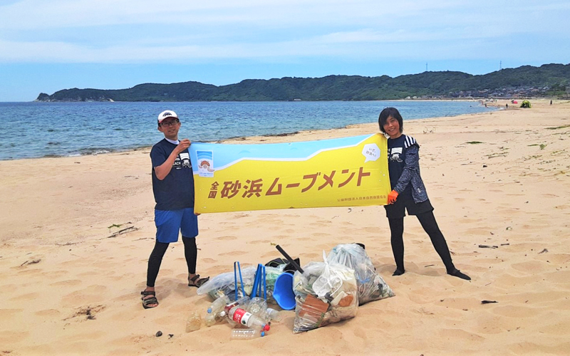 砂浜ムーブメント横断幕を持つスタッフの写真