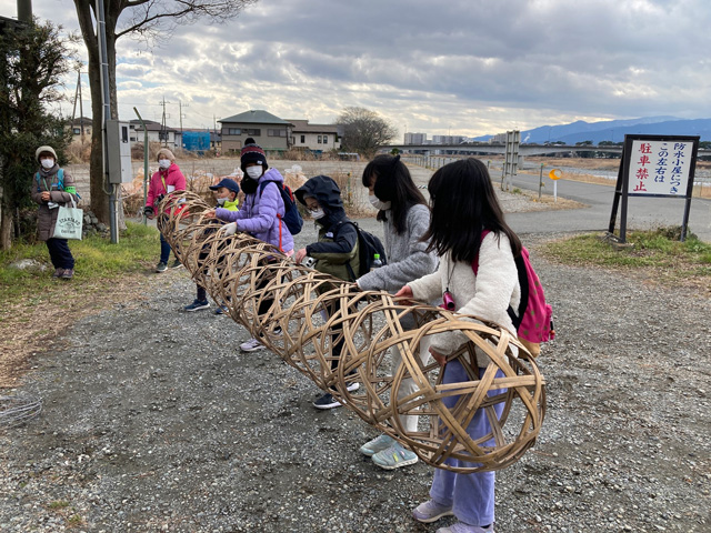 蛇籠を持つ子どもたちの写真