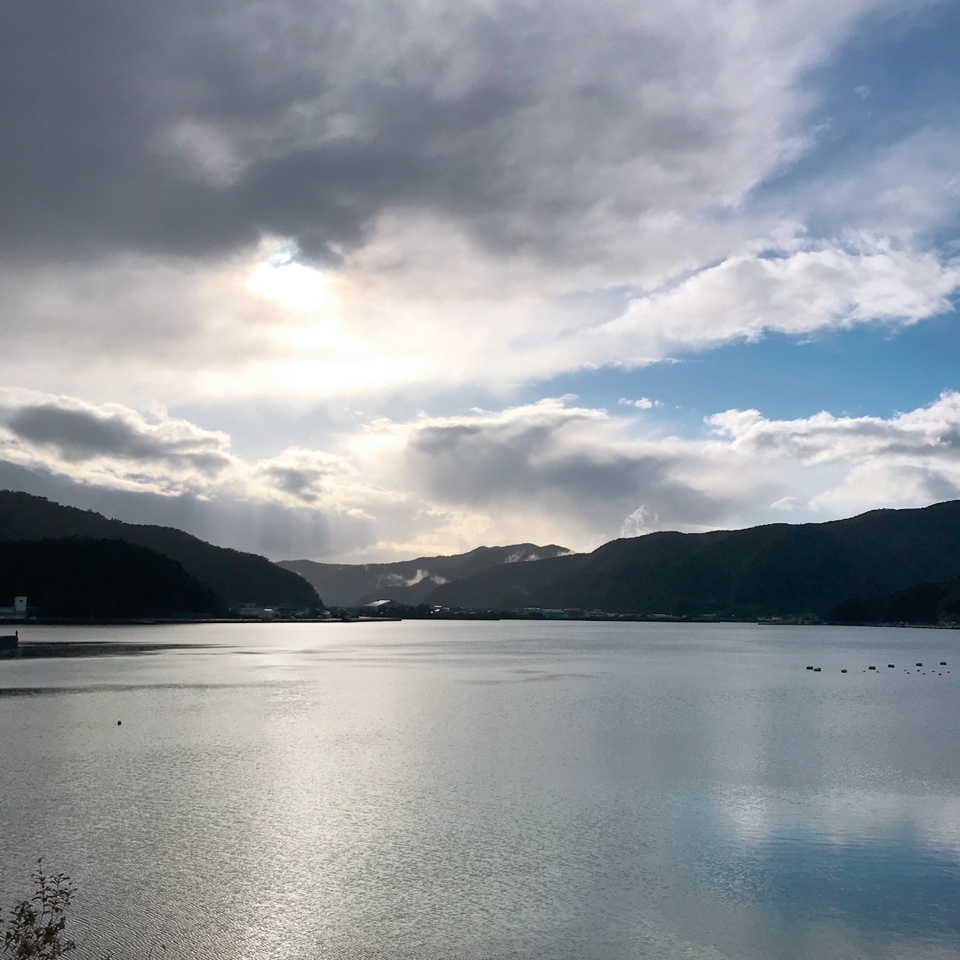 雲の間から日が差す焼内湾の写真