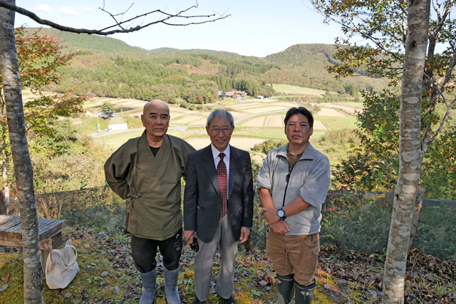 里山風景をバックに亀山理事長と住職、イーハトーブのスタッフ