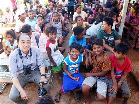屋外の教室で大勢の子供たちと山﨑さん写真