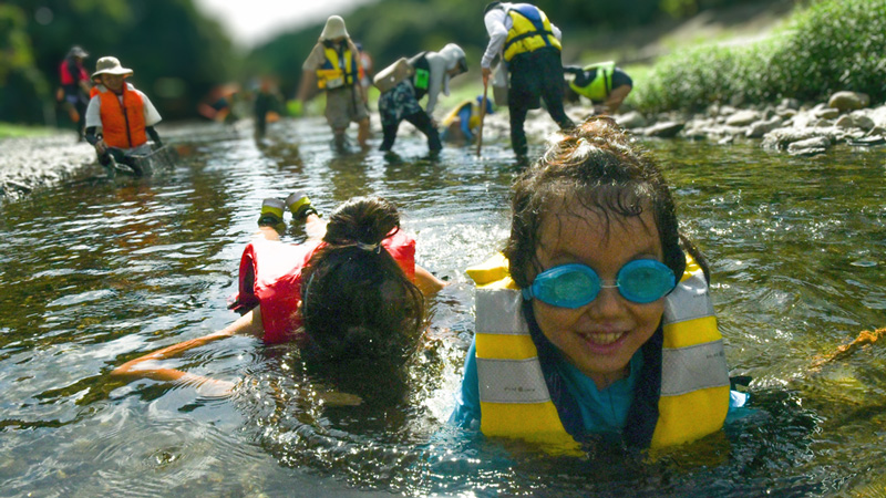 水中眼鏡を着けて川の中を覗く子どもの画像