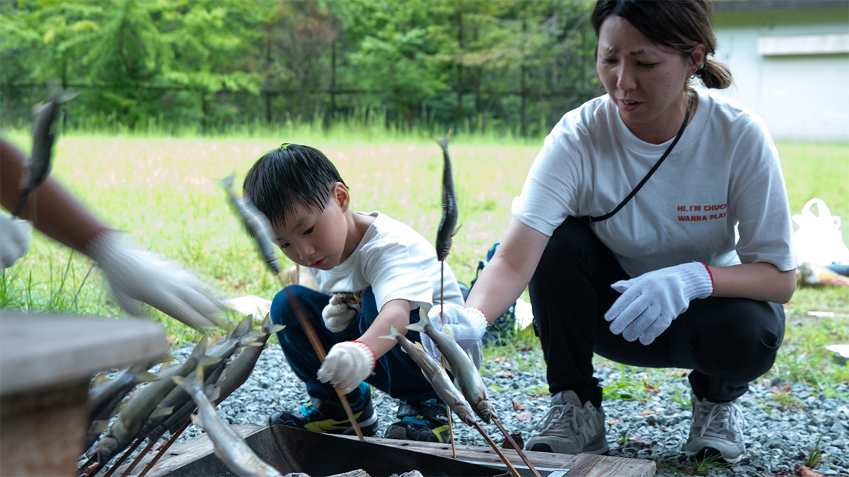 囲炉裏でアユを焼く親子の写真