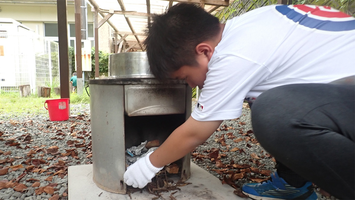 かまどに火をくべる子どもの写真