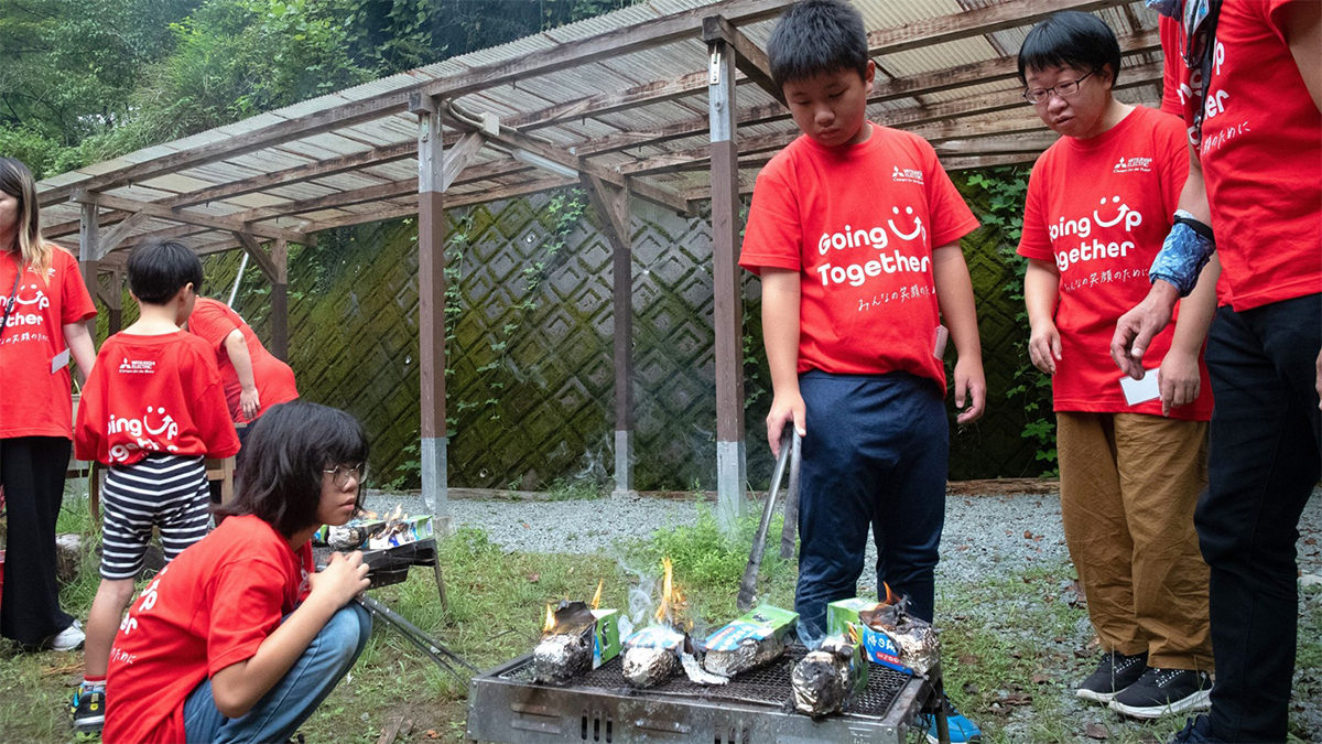 バーベキューグリルでカートンドッグを焼く子どもたちの写真