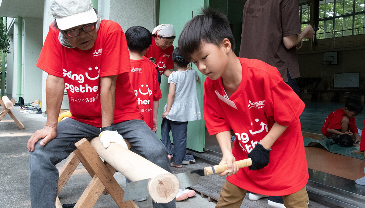 ノコギリで木を切る子どもの写真