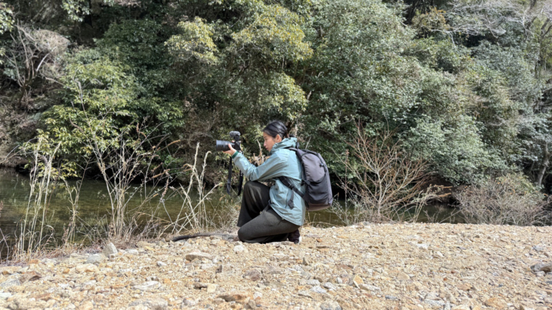 屋外で一眼レフカメラを構える金さんの写真