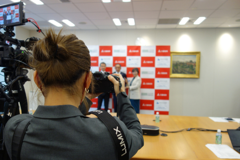 会見場でカメラを構える金さんの後ろ姿